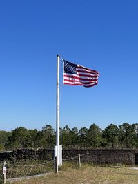 Low angle view of american flag against clear blue sky