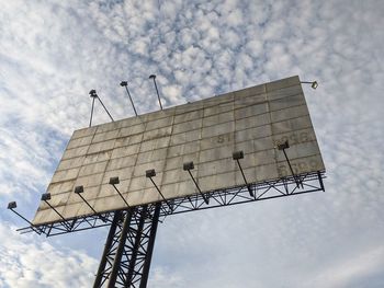 Low angle view of crane by building against sky