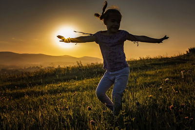 Silhouettes of kids walking forward to rising sun in mountains at summer, healthy family vacation