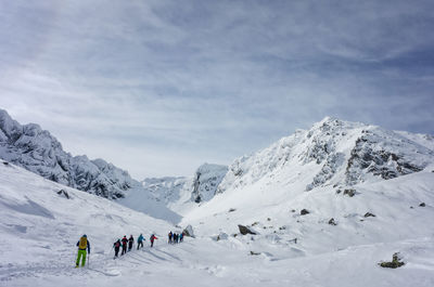 People on snowcapped mountain against sky