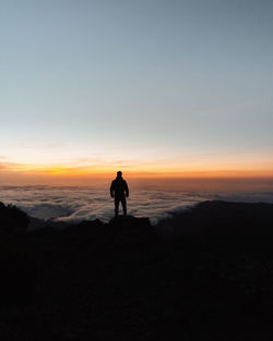 Silhouette man standing on shore against sky during sunset