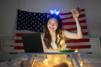 Smiling young woman using phone while sitting on table