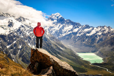 Rear view of man standing on snowcapped mountain