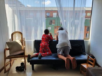 Rear view of grandfather with grandson looking through window at home