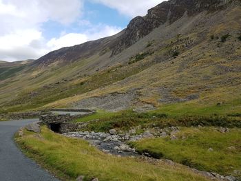 Scenic view of stream by mountains against sky