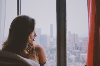 Rear view of woman looking through window