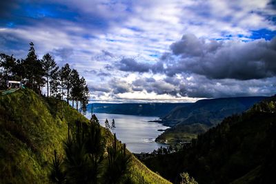 Scenic view of river by mountains against sky