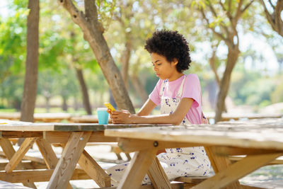 Side view of young woman sitting on table