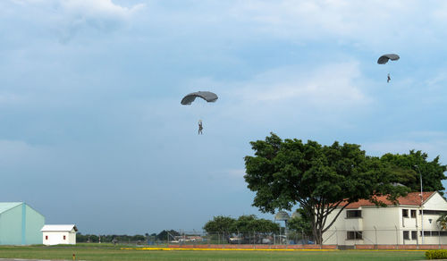 Kite flying over trees against sky