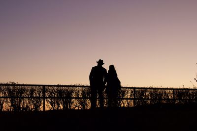 Silhouette men standing against clear sky during sunset