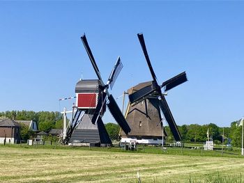 Traditional windmill on field against clear sky