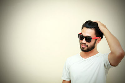 Young man wearing sunglasses standing gray background