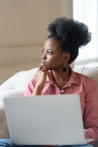 Woman looking away by laptop on table
