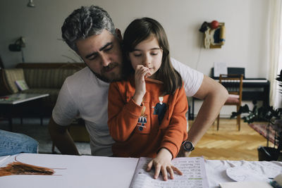 Girl doing homework with father at table