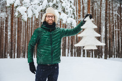 Young man standing in snow covered forest