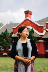 Beautiful young woman standing against built structure against sky