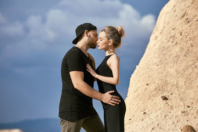 Young couple standing against sky