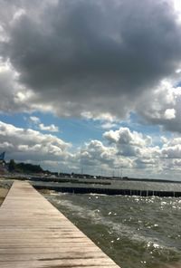 Pier on sea against cloudy sky