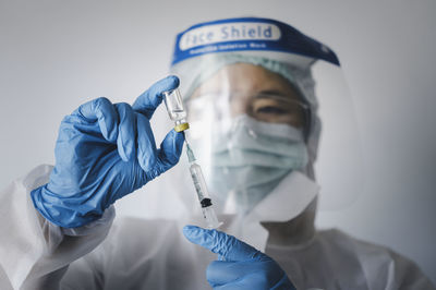 Close-up of doctor wearing surgical mask against white background