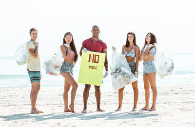 Portrait of activist holding plastic bags while standing at beach