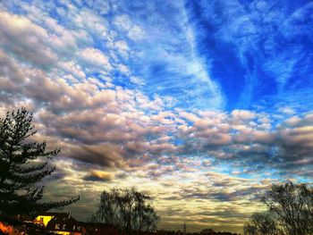 Low angle view of silhouette trees against dramatic sky