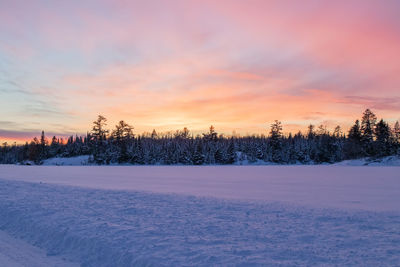 Scenic view of snow covered field against sky during sunset
