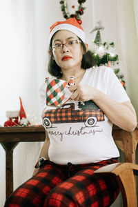 Portrait of young woman sitting on chair at home