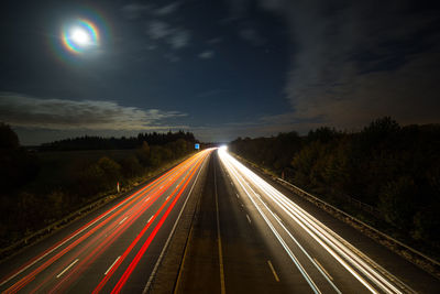 Light trails on road against sky at night