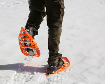 Low section of woman snowshoeing on snowy field