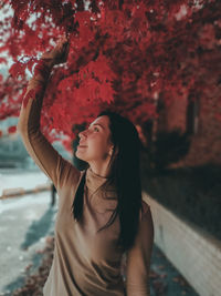 Portrait of young woman standing against tree