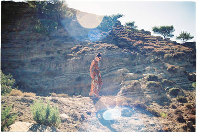 Fashionable woman walking on dirt against rock formation