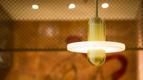 Low angle view of illuminated light bulb hanging on ceiling