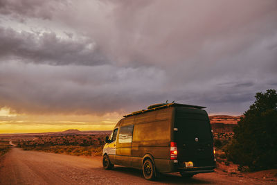 Camper van off side of dirt road during golden sunset in moab, utah.