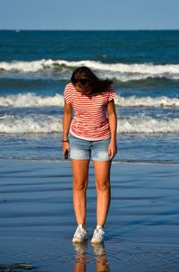 Rear view of woman standing on beach against sea