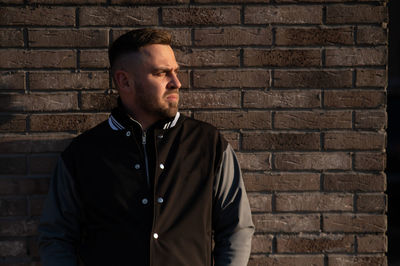 Young man standing against brick wall