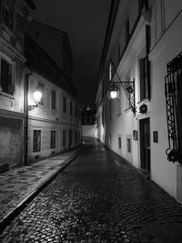 Empty alley amidst buildings at night