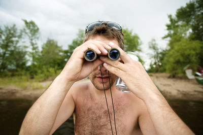 Man holding binoculars while standing in sea