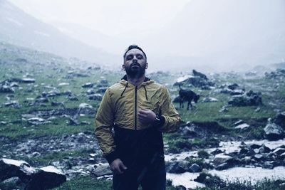 Young man standing on land during rainy season