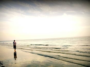 Rear view of man at beach against sky