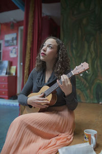 Young female musician practicing the ukulele