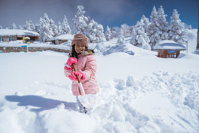 Portrait of smiling woman standing on snow covered field