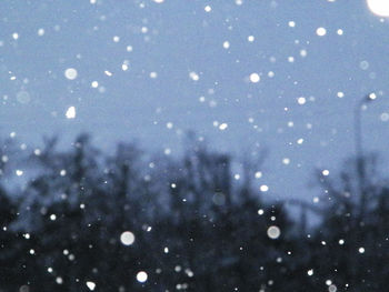 Defocused image of illuminated lights against blue sky