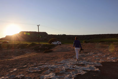 Rear view of man standing on street against sky