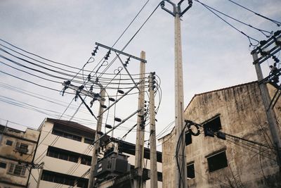Low angle view of electricity pylon and buildings against sky