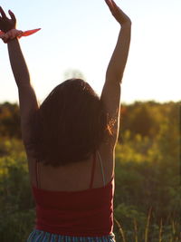 Rear view of woman standing on field against sky