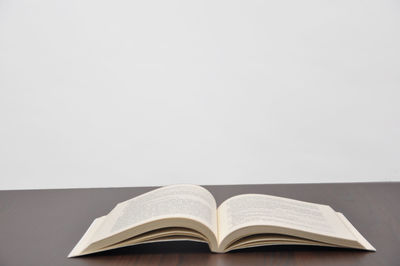 Close-up of open book on table against white background