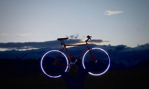 Illuminated bicycle parked on field against sky at dusk