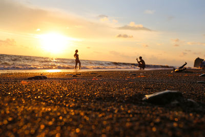 People on beach against sky during sunset