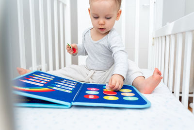 Cute boy playing with toys on bed at home