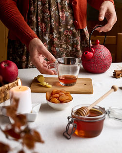 Cozy autumn days. woman brew tea in red teapot on the table with linen tablecloth. fall vibes. 